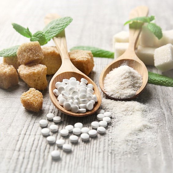 Zuckerersatz Stevia bei Fructoseintoleranz auf Holzlöffel in Tablettenform, als Blatt und als Steviapulver