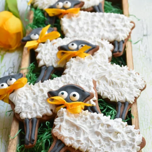 Osterlämmchen aus Mürbteig mit royal Icing auf grünem Hintergrund in Holzschale