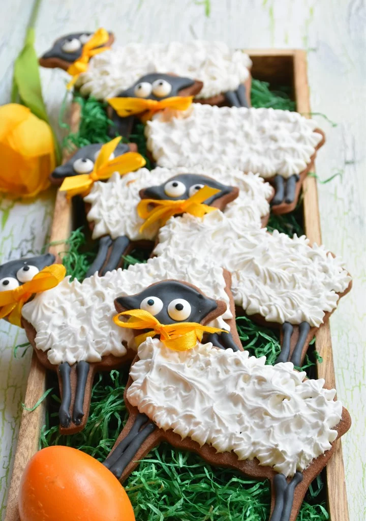 Osterlämmchen aus Mürbteig mit royal Icing auf grünem Hintergrund in Holzschale