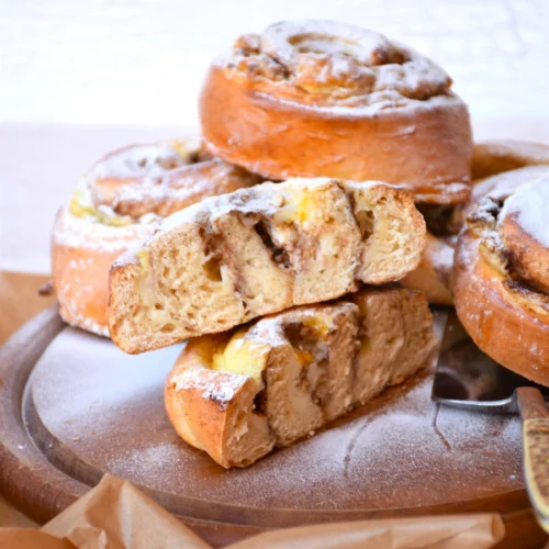 Fructosearme Hefeschnecken mit Vanillepuddingfülle und Zimt auf Holzteller