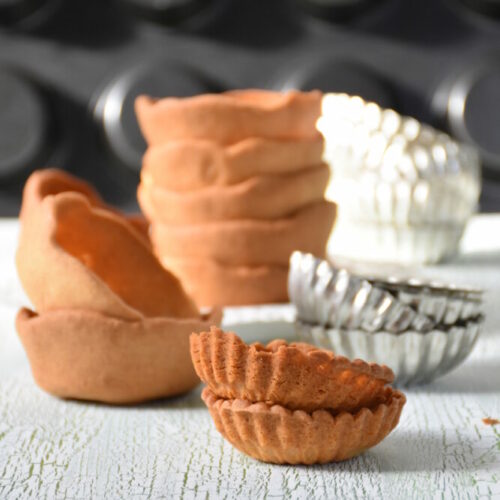Fructosearme Mürbteigtartelettes selber machen, gestapelt, im Hintergrund Muffinblech und Aluförmchen