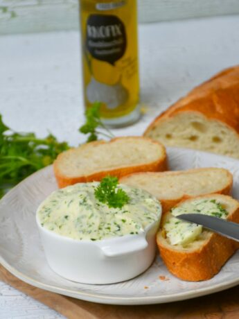 Kräuterbutter ohne Fructose mit KNOFIX-Knoblauchöl, bestrichenes Weißbrot auf Holzbrett