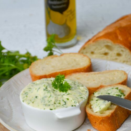 Kräuterbutter ohne Fructose mit KNOFIX-Knoblauchöl, bestrichenes Weißbrot auf Holzbrett