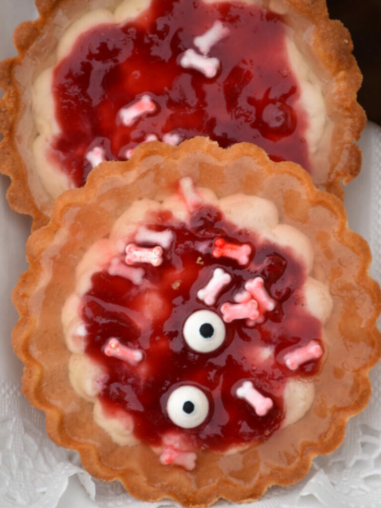 Halloweentörtchen, gruselig mit Topfenfülle, roter Marmelade und Zuckerkonochen, Zuckeraugen