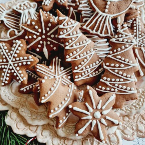 Lebkuchen ausgestochen inverschiedenen Formen mit Zitronenglasur verziert auf rosa Spitzenteller